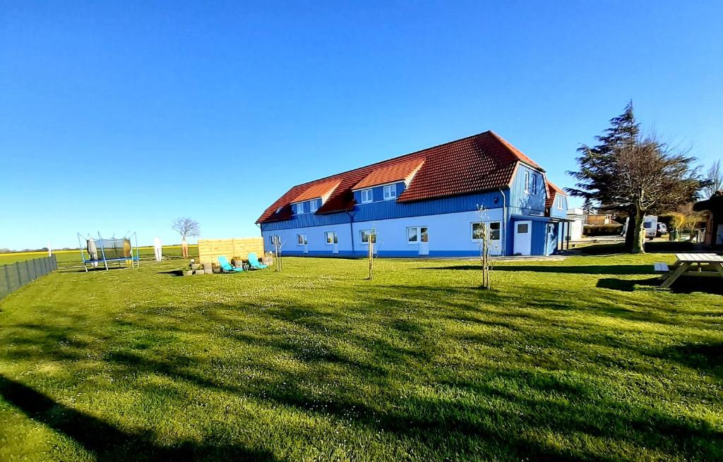 a blue building with a red roof on a grass field at Gästehaus Sulsdorf - Adults only in Sulsdorf auf Fehmarn