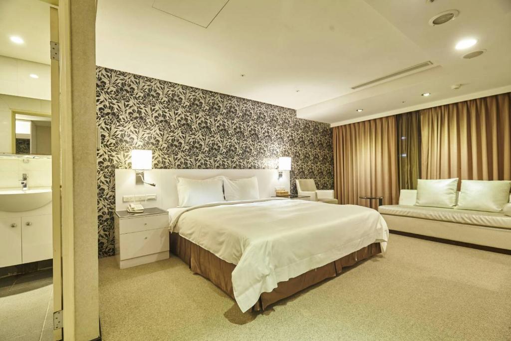 a bedroom with a large white bed and a couch at Family Hotel Taipei in Zhonghe