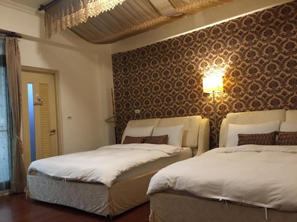 two beds in a room with a wall at Amicasa Guesthouse in Hualien City