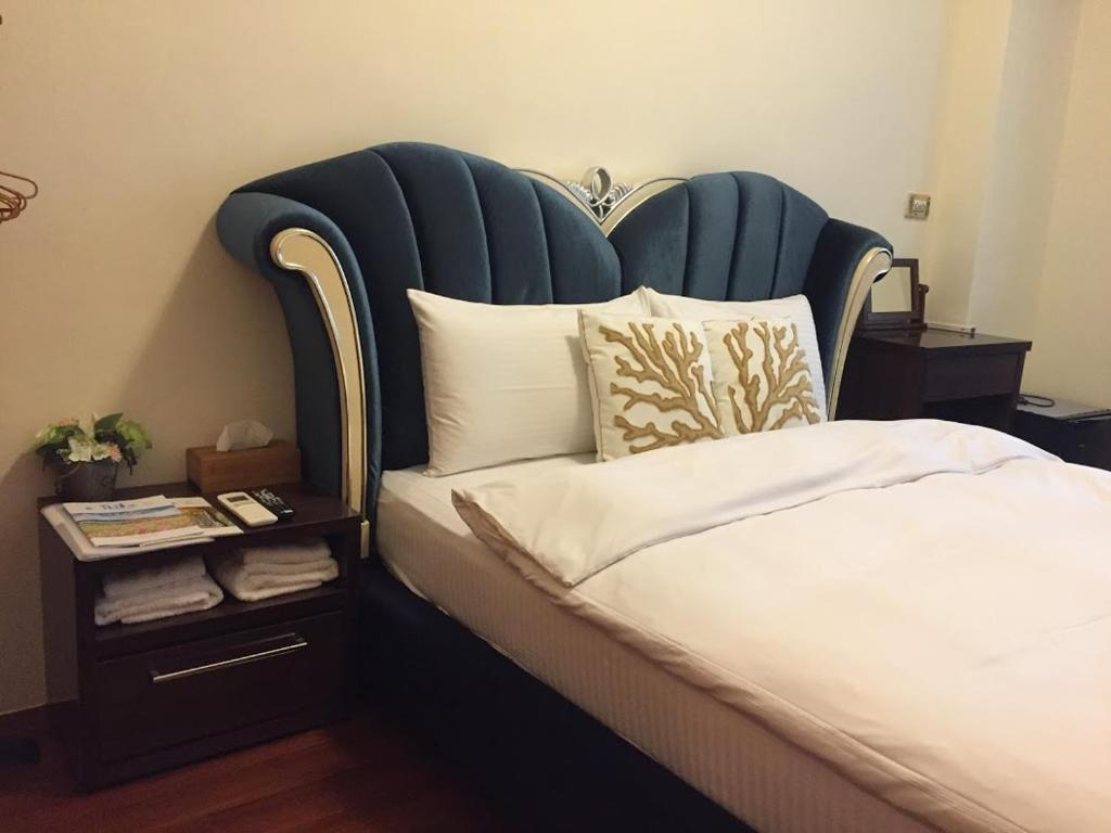 a bed with a blue headboard and a side table at Amicasa Guesthouse in Hualien City