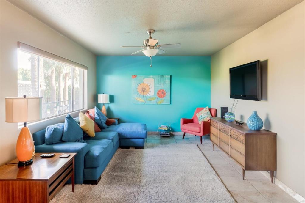 sala de estar con sofá azul y TV en Mid century modern condo near Old Town, pool & BBQ, en Scottsdale