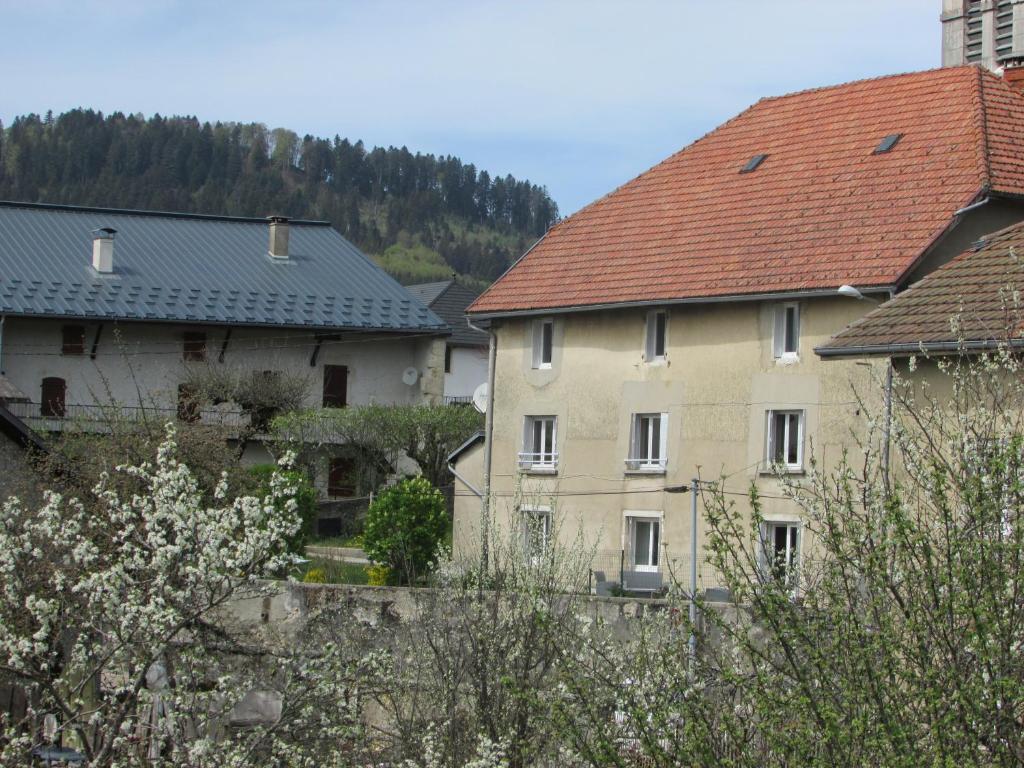 Brénod的住宿－Le Clos Marie，两栋房子旁边一座红色屋顶的建筑
