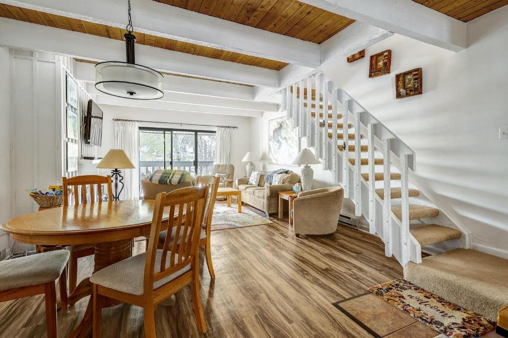 a living room with a table and chairs and a staircase at Peaceful creek view from the deck! Walk to Shuttle in Vail