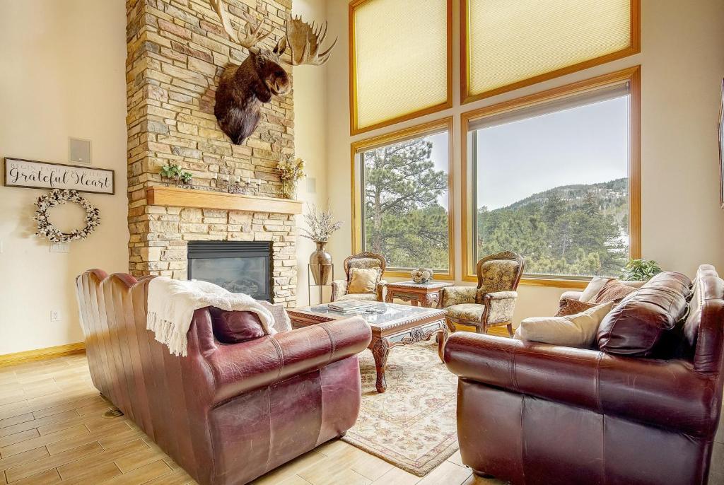 a living room with leather furniture and a stone fireplace at Secluded & Spacious Mountain Getaway in Morrison