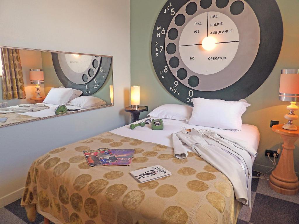 ein Schlafzimmer mit einem Bett mit einer großen Uhr an der Wand in der Unterkunft Detective Hotel in Étretat
