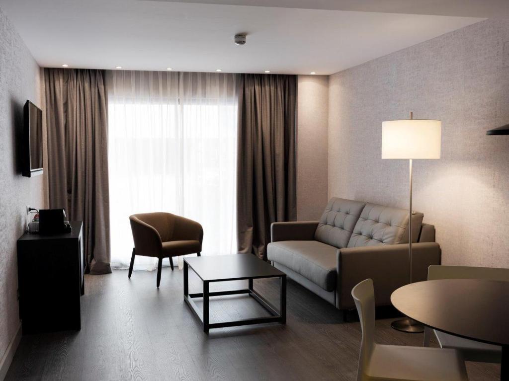HG City Suites Barcelona في برشلونة: غرفة معيشة مع أريكة وطاولة