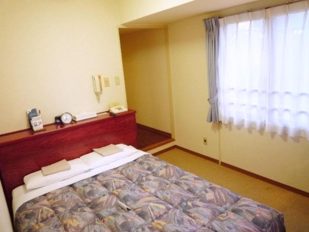 1 dormitorio con cama y ventana en Sky Heart Hotel Kawasaki / Vacation STAY 80809, en Kawasaki