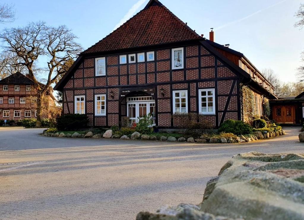 a large brown house with white windows on a street at Landhotel Bauernwald in Faßberg