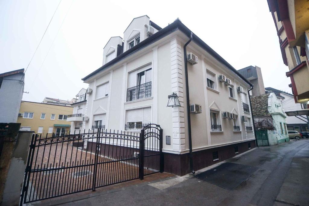 un bâtiment blanc avec une clôture devant lui dans l'établissement Live & Sleep, à Novi Sad