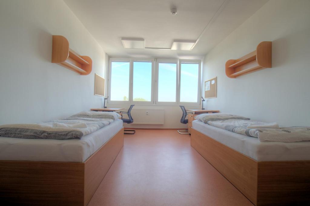 um quarto com três camas e uma janela em Domov mládeže - Ubytování Sokolov em Sokolov