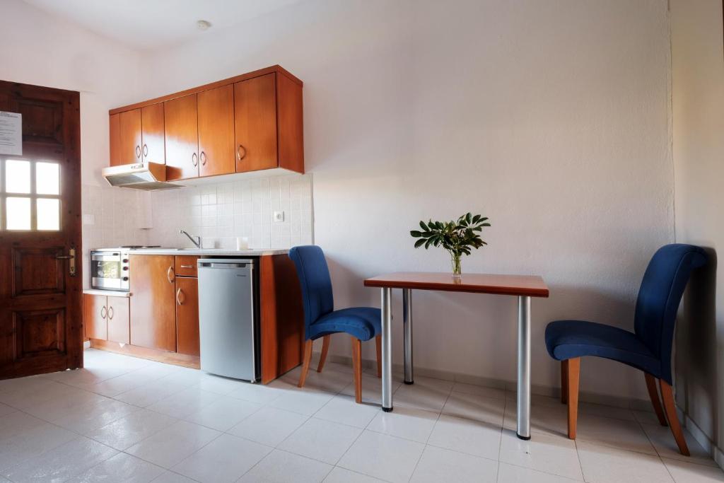 a small kitchen with a table and blue chairs at Hotel Club Maria Sidari in Sidari