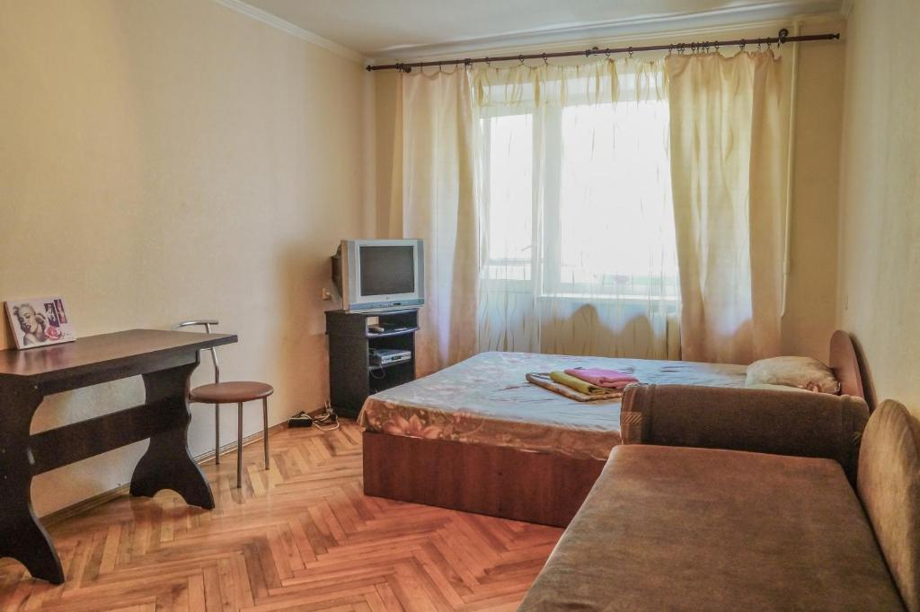 Schlafzimmer mit einem Bett, einem Schreibtisch und einem TV in der Unterkunft Квартира по улице Лескова, 6 in Kiew