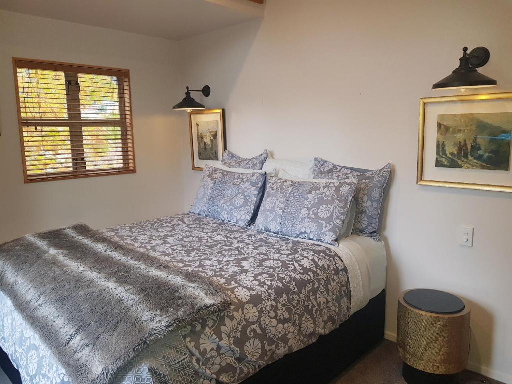 a bedroom with a bed with a blanket and pillows at Villa 10 - Central Stylish Apartment in Queenstown