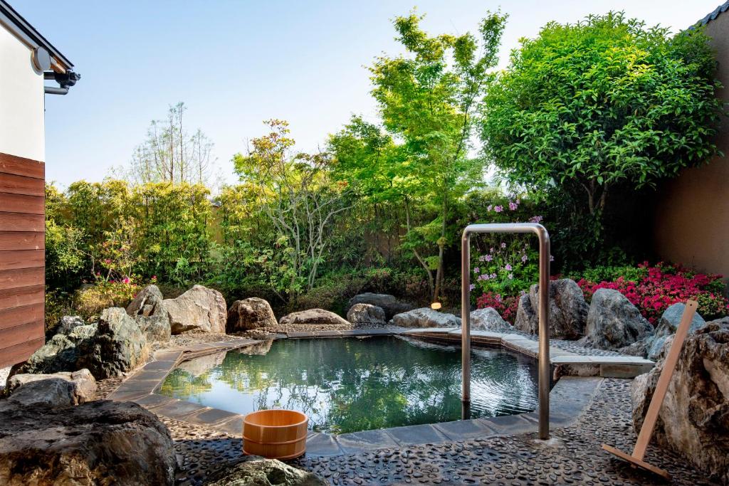 a small pool in a garden with rocks at Kannawaen in Beppu