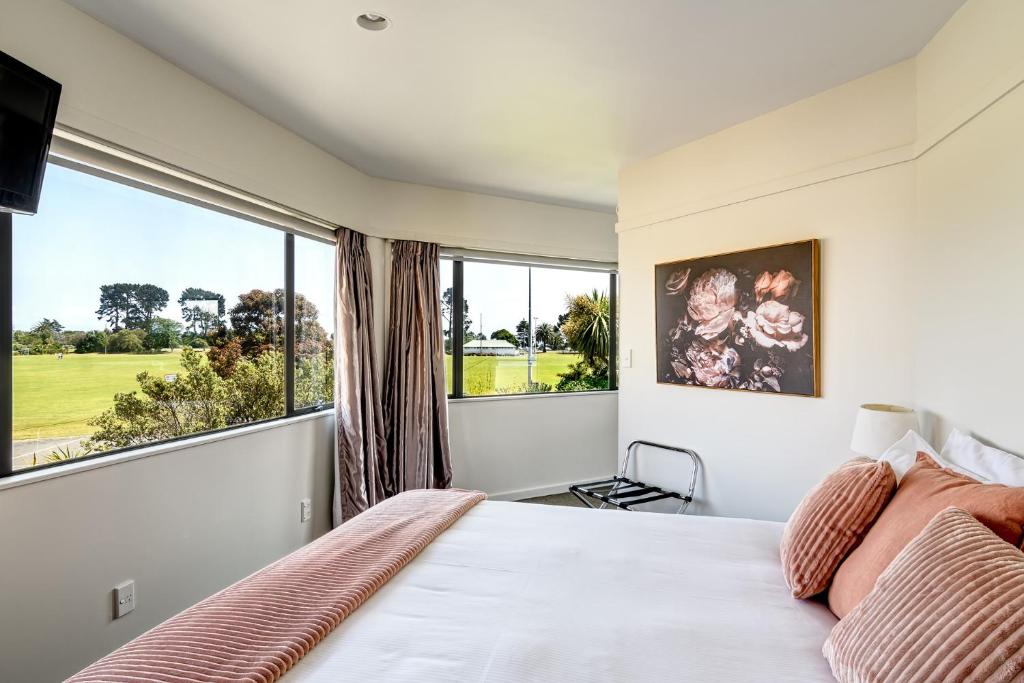 
a bedroom with a large bed and a large window at The Beachcomber Hotel in Nelson
