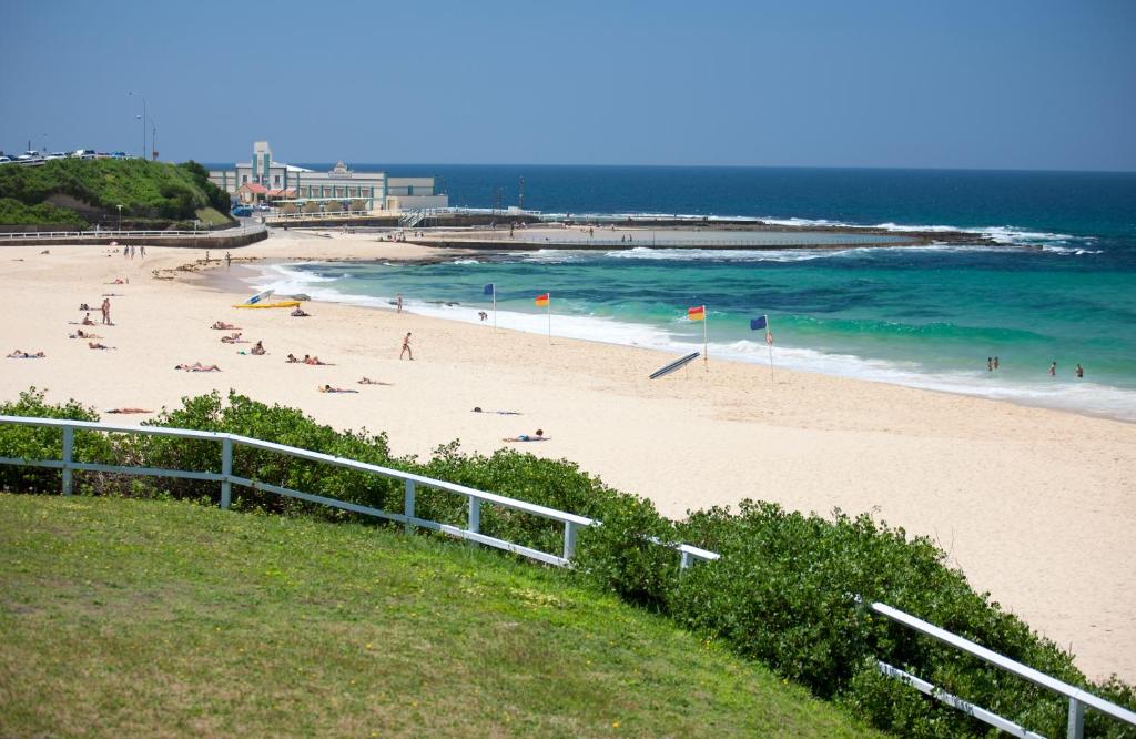 a beach with people on the sand and the ocean at Novotel Newcastle Beach in Newcastle