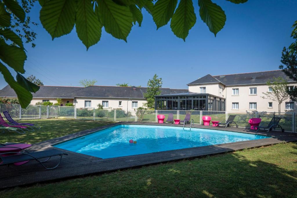 a swimming pool in the yard of a house at The Originals City, Hôtel La Saulaie, Saumur Ouest in Doué-la-Fontaine