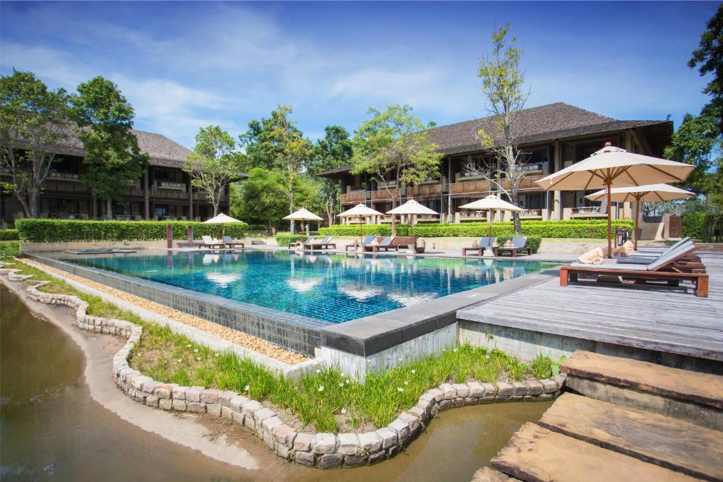 een zwembad met banken en parasols voor een resort bij Kirimaya Golf Resort Spa - SHA Plus Certified in Mu Si