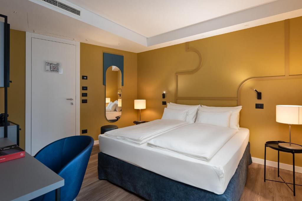 um quarto com uma grande cama branca e uma secretária em HT Hotel Trieste em Gradisca dʼIsonzo