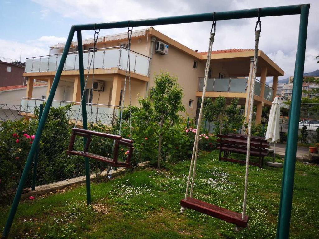 a swing set in a yard with a house at Apartmani Becici in Bečići