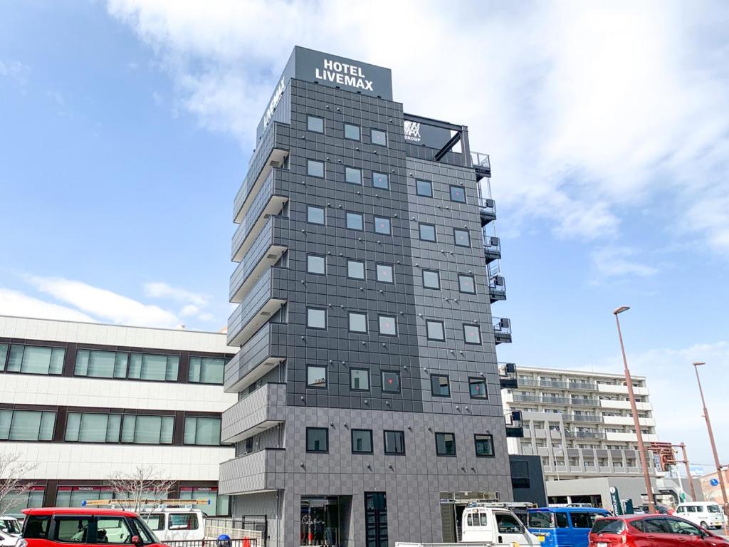 wysoki szary budynek z napisem w obiekcie HOTEL LiVEMAX Okayama Kurashiki Ekimae w mieście Kurashiki