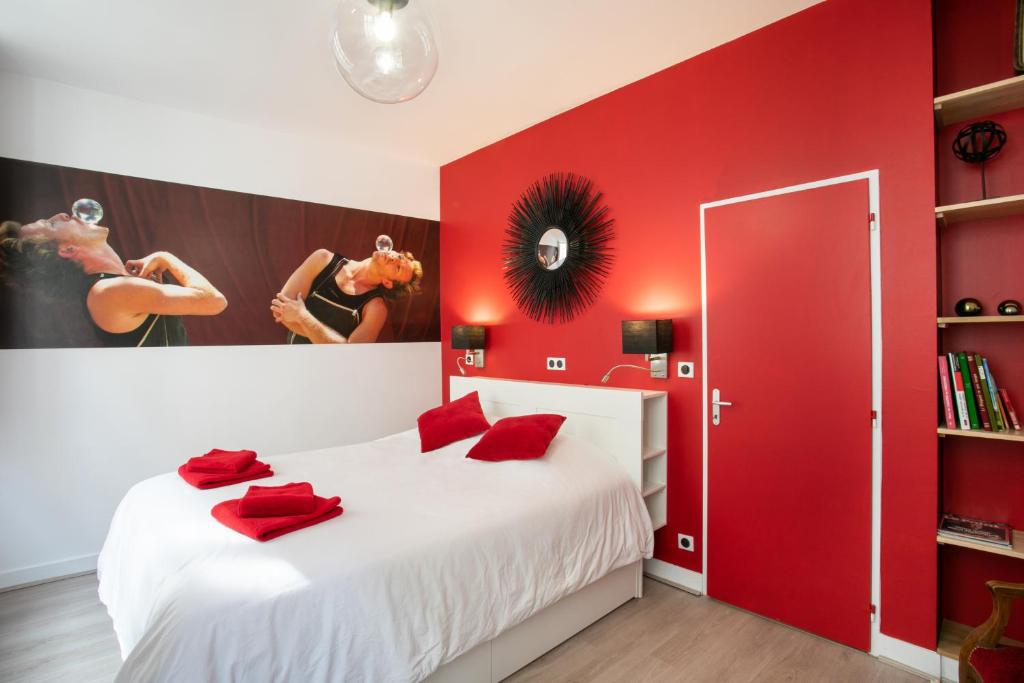 a bedroom with red walls and a white bed with red pillows at Corps et graphi(qu)es in Périgueux