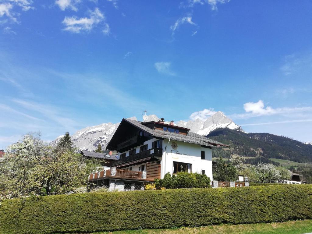 una casa en una colina con montañas en el fondo en Sonneck Pension en Pfarrwerfen