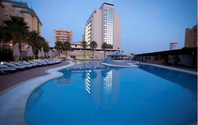 une grande piscine avec des chaises et un bâtiment dans l'établissement 4Us LA MANGA VIP HOTEL, à La Manga del Mar Meno