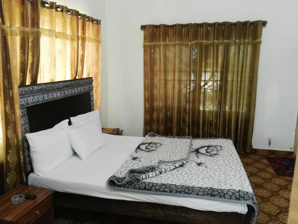 a bedroom with a bed with white sheets and pillows at KHYBER INN in Islamabad