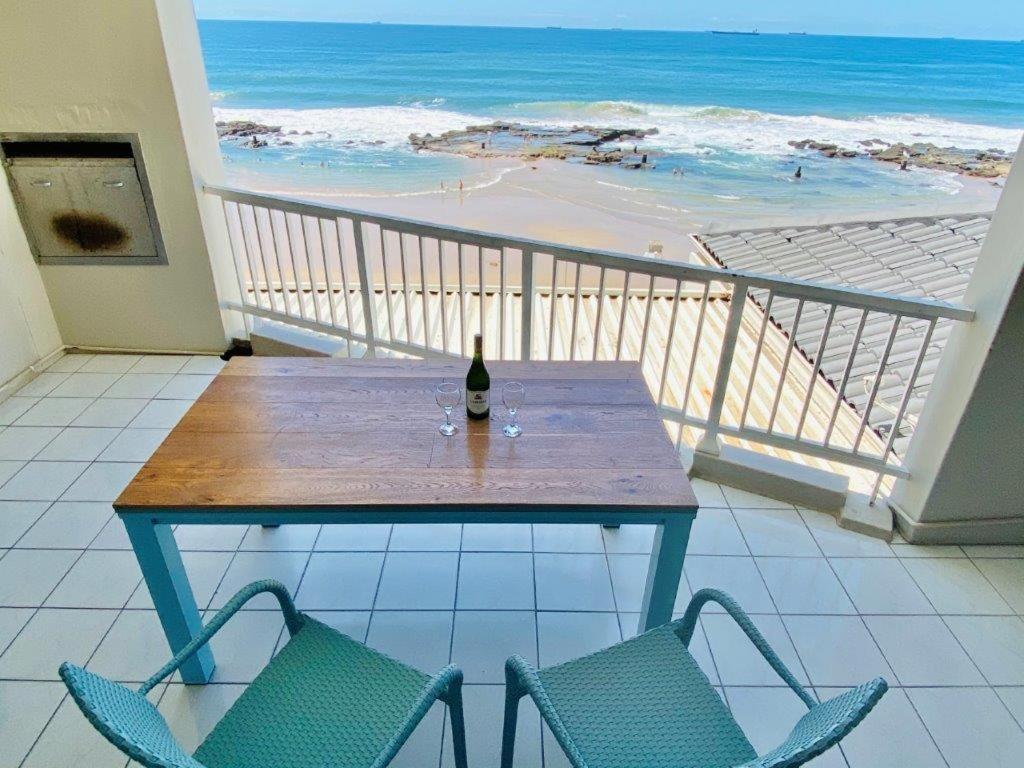 a table with a bottle of wine on a balcony with a beach at Sorgente 304 with Inverter in Umdloti