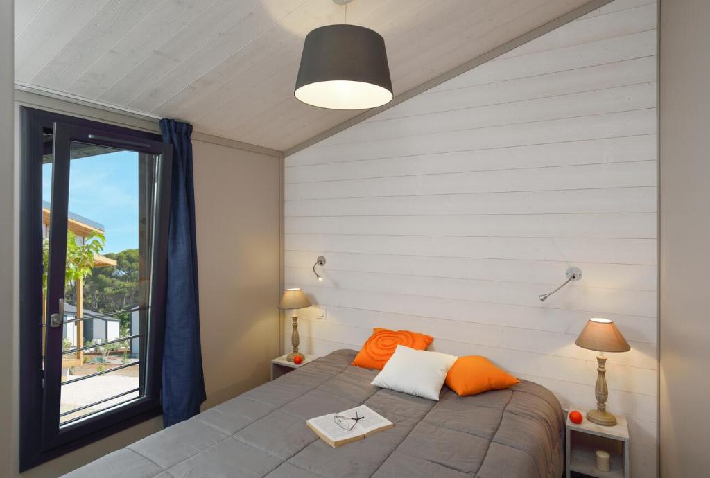 een slaapkamer met een bed met oranje kussens en een raam bij Nature Holiday's Domaine La Grenatière in Pomérols
