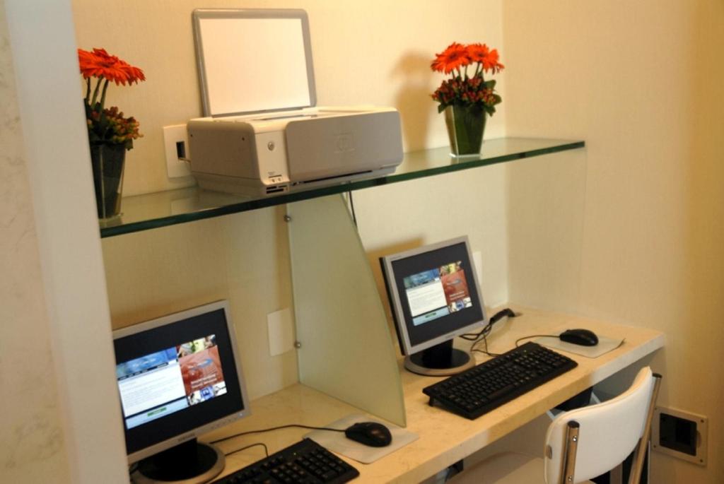 a desk with two monitors and a computer on it at Sol Ipanema Hotel in Rio de Janeiro