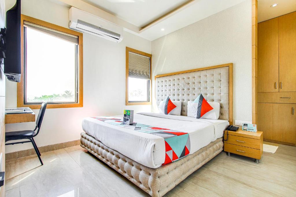 a bedroom with a large bed and a chair in it at FabHotel Naman Palace in Bhopal