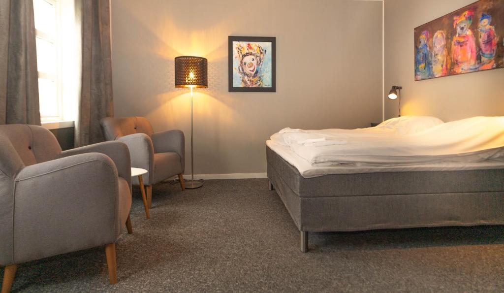 ein Schlafzimmer mit einem Bett, Stühlen und einer Lampe in der Unterkunft Mosjøen Romutleie - Sentrum in Mosjøen