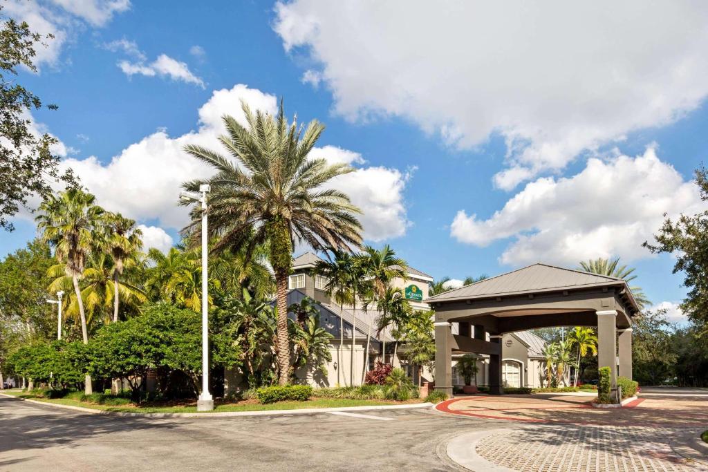 a building with a pavilion next to a street with palm trees at La Quinta by Wyndham Ft. Lauderdale Plantation in Plantation