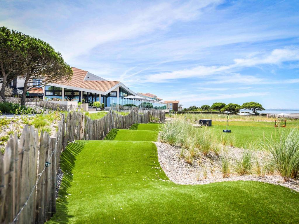 einen Garten mit grünem Gras und einem Holzzaun in der Unterkunft La Grande Terrasse Hotel&Spa La Rochelle MGallery Hotel Collection in Châtelaillon-Plage