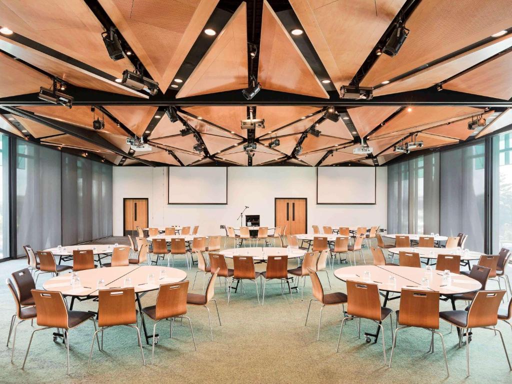 a large room with tables and chairs in it at Novotel Auckland Airport in Auckland