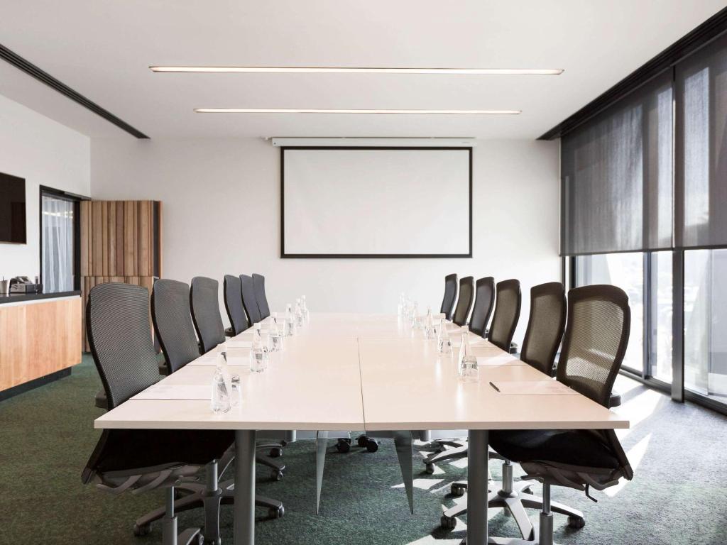 a large conference room with a long table and chairs at Novotel Auckland Airport in Auckland