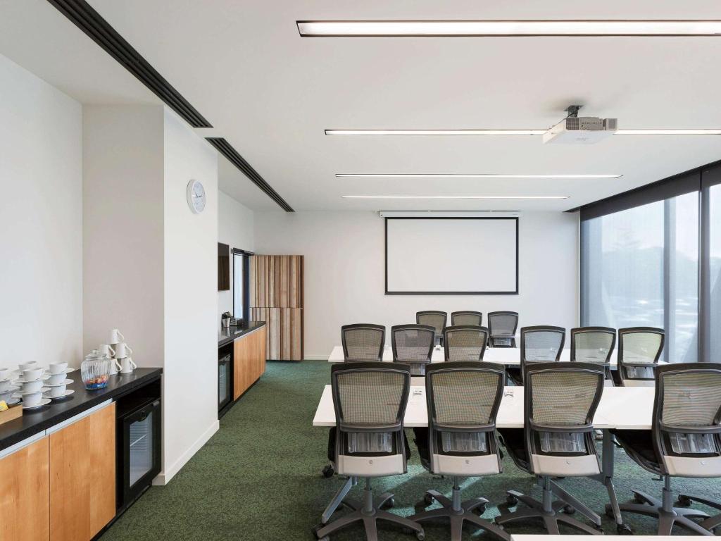 a conference room with a long table and chairs at Novotel Auckland Airport in Auckland