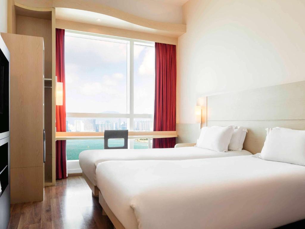 a hotel room with two beds and a large window at Ibis Hong Kong Central & Sheung Wan in Hong Kong