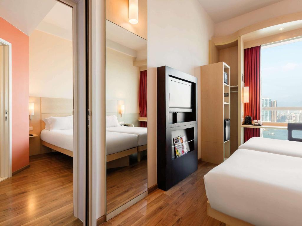 a hotel room with two beds and a mirror at Ibis Hong Kong Central & Sheung Wan in Hong Kong