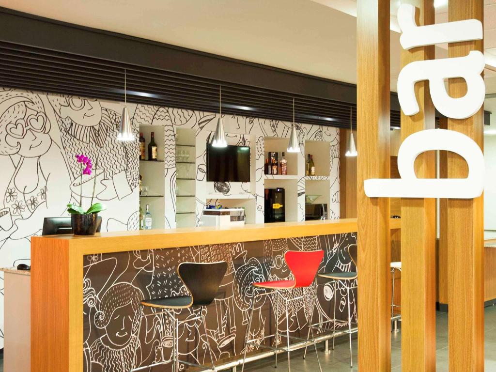 a bar with two red chairs in a restaurant at ibis Cascavel in Cascavel