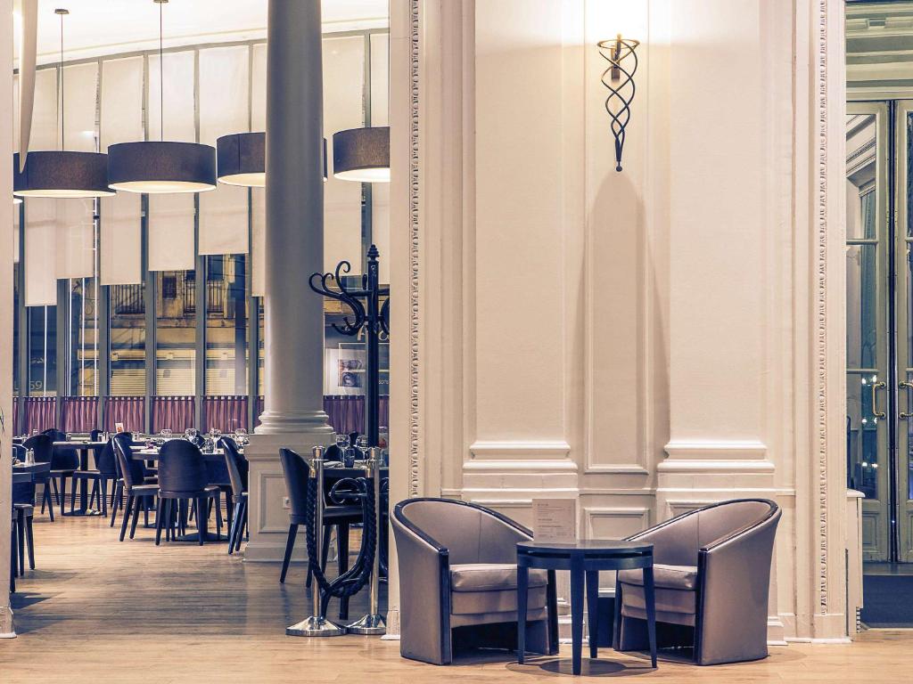 eine Reihe von Tischen und Stühlen in einem Restaurant in der Unterkunft Mercure Lille Roubaix Grand Hôtel in Roubaix