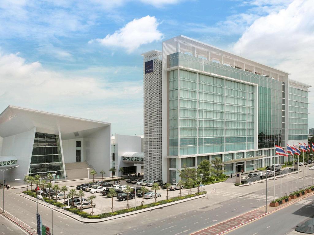 a large building with cars parked in a parking lot at Novotel Bangkok IMPACT in Nonthaburi