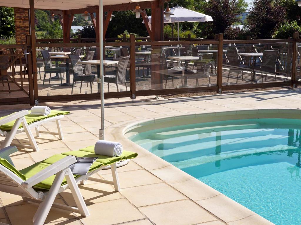 uma piscina com cadeiras, um guarda-sol e uma mesa em ibis Styles Périgueux Trélissac em Trélissac