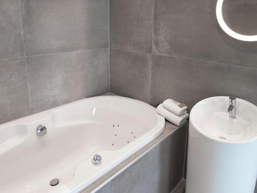 a bathroom with a tub and a sink at ibis Styles Nivelles in Nivelles
