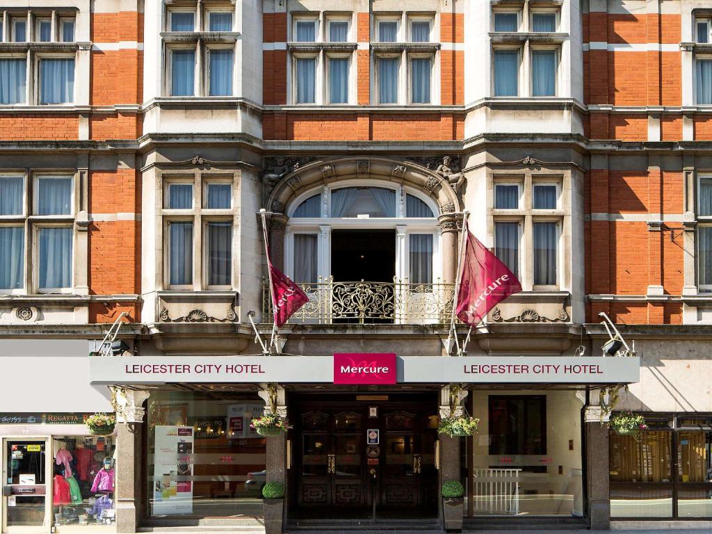 a building with red flags in front of it at Jupiter Hotel Leicester The Grand in Leicester