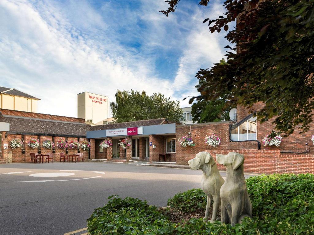 two statues of dogs sitting in front of a building at Mercure Maidstone Great Danes Hotel in Maidstone