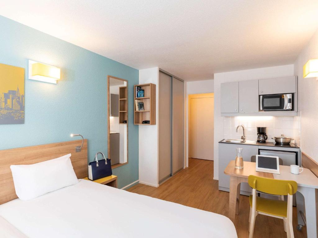 a hotel room with a bed and a desk and a kitchen at Aparthotel Adagio Access La Défense - Place Charras in Courbevoie