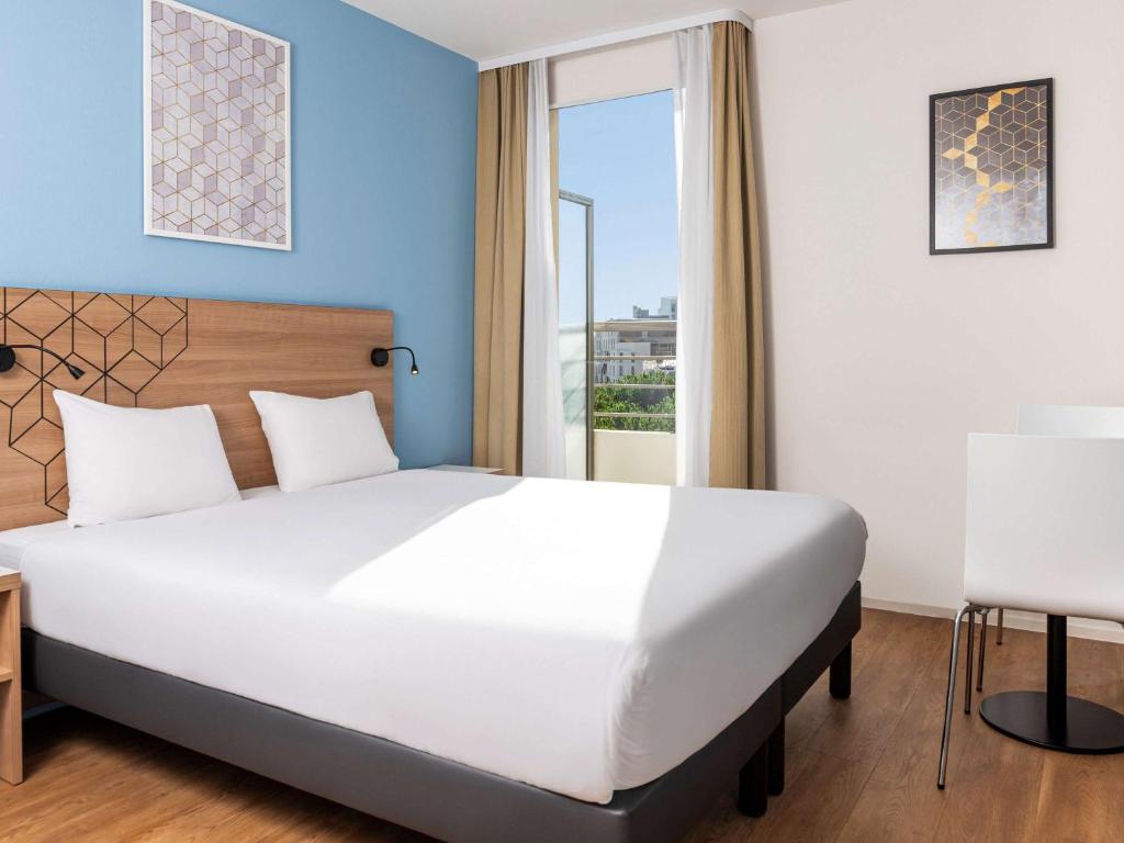 une chambre avec un grand lit blanc et une fenêtre dans l'établissement Aparthotel Adagio Access Paris Quai d'Ivry, à Ivry-sur-Seine